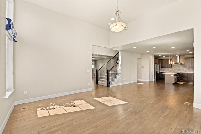 unfurnished living room featuring a towering ceiling and light hardwood / wood-style floors