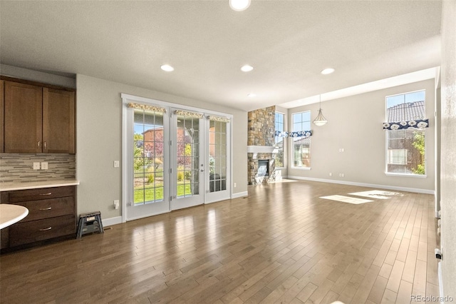 exercise room featuring a stone fireplace, plenty of natural light, and hardwood / wood-style floors