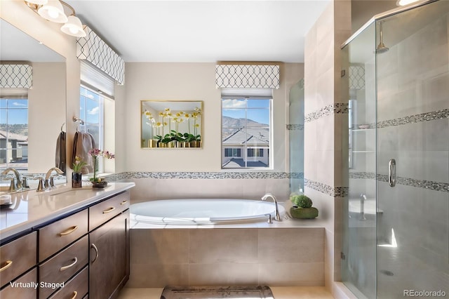 bathroom with independent shower and bath, vanity, and a wealth of natural light