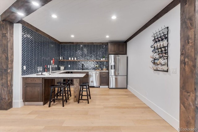 15116 Lyons Ridge Dr, Morrison, CO 80465 - kitchen with decorative backsplash, a breakfast bar area, recessed lighting, light countertops, and appliances with stainless steel finishes