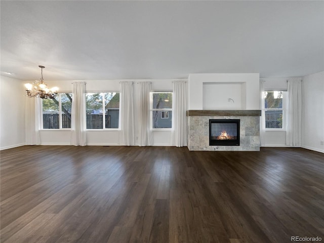 unfurnished living room with a tile fireplace, dark wood-type flooring, and a notable chandelier