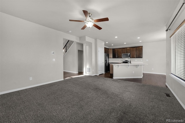 unfurnished living room with dark carpet and ceiling fan