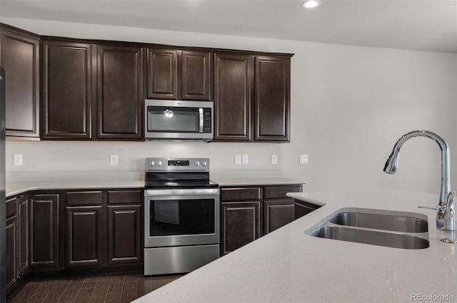 kitchen featuring light stone countertops, dark brown cabinets, stainless steel appliances, and sink