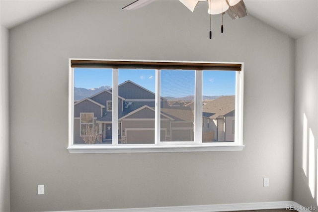 empty room with a mountain view, plenty of natural light, ceiling fan, and vaulted ceiling