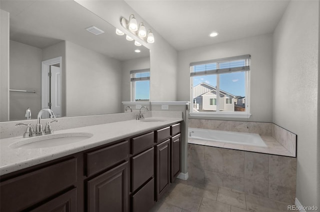 bathroom featuring tile patterned flooring, vanity, and a relaxing tiled tub