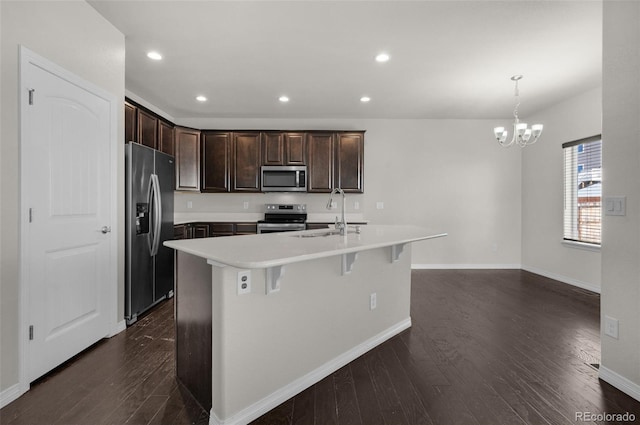 kitchen with sink, dark hardwood / wood-style floors, pendant lighting, a center island with sink, and appliances with stainless steel finishes