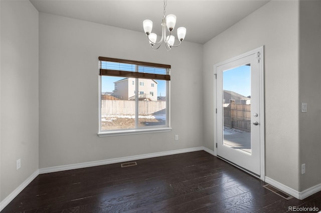 unfurnished dining area featuring a notable chandelier, a healthy amount of sunlight, and dark hardwood / wood-style floors