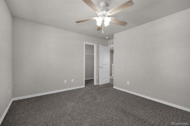 unfurnished bedroom featuring ceiling fan, a closet, a spacious closet, and dark colored carpet