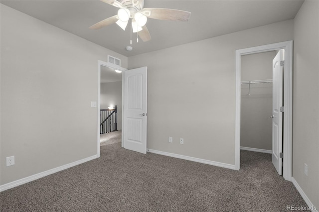 unfurnished bedroom featuring ceiling fan, a spacious closet, carpet floors, and a closet