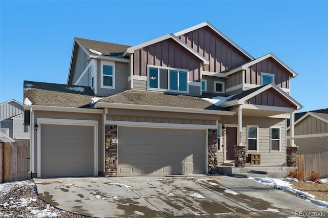 6677 Lamine Dr, Colorado Springs, CO 80925 - view of front of house featuring driveway, stone siding, fence, board and batten siding, and an attached garage