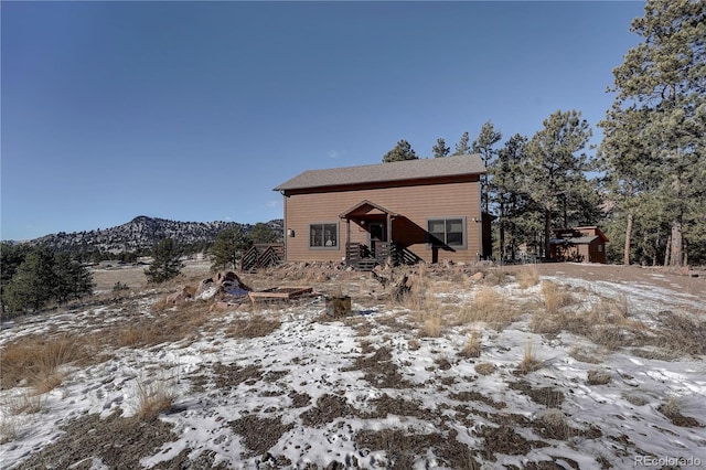 snow covered rear of property featuring a mountain view