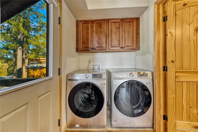 laundry room with washing machine and clothes dryer and cabinets