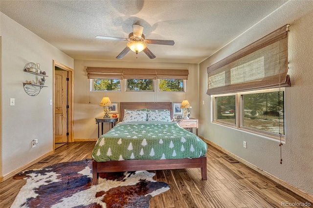 bedroom with ceiling fan, wood-type flooring, and a textured ceiling