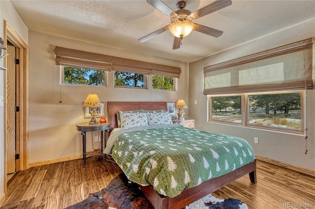 bedroom featuring ceiling fan, wood-type flooring, and a textured ceiling