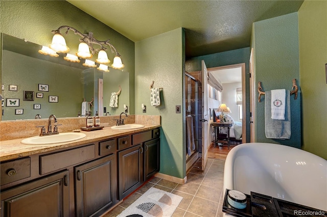 bathroom featuring a textured ceiling, walk in shower, vanity, and tile patterned flooring