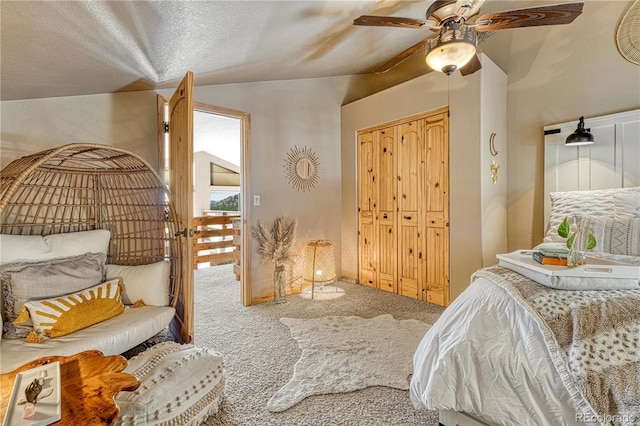 bedroom with ceiling fan, carpet floors, a closet, lofted ceiling, and a textured ceiling