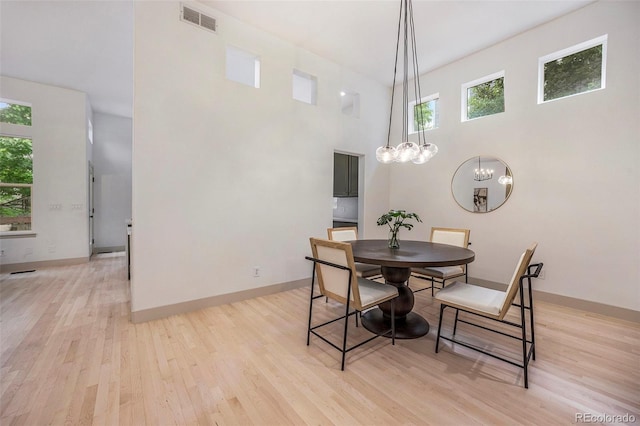 7410 Winter Berry Ln, Castle Pines, CO 80108 - dining space with plenty of natural light, light wood-style flooring, a chandelier, and a towering ceiling