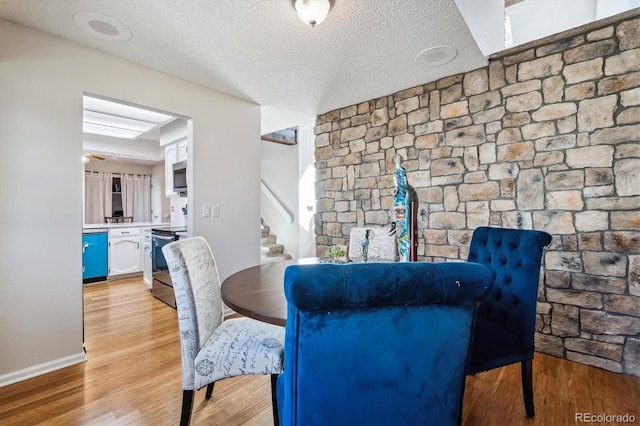 dining area featuring a textured ceiling, wood finished floors, and stairs