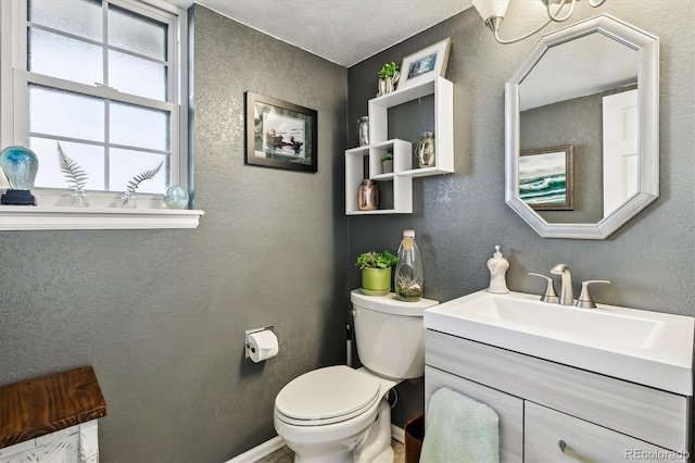 half bathroom with a textured wall, vanity, and toilet