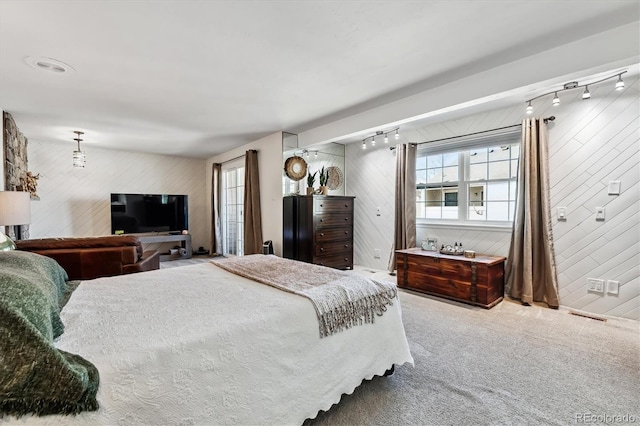 bedroom featuring wood walls, carpet flooring, visible vents, and track lighting