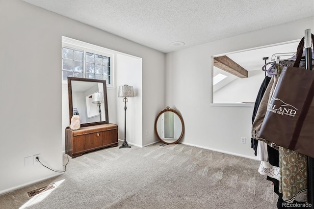 carpeted bedroom featuring a textured ceiling, visible vents, and baseboards