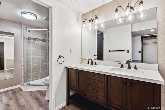 full bathroom with a textured ceiling, wood finished floors, a stall shower, and a sink