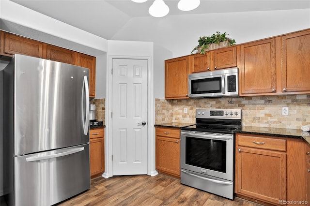 5337 S Ukraine Way, Aurora, CO 80015 - kitchen featuring stainless steel appliances, brown cabinets, wood finished floors, backsplash, and lofted ceiling