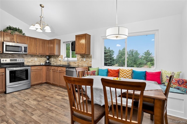 5337 S Ukraine Way, Aurora, CO 80015 - kitchen featuring appliances with stainless steel finishes, tasteful backsplash, lofted ceiling, light wood-style floors, and dark countertops