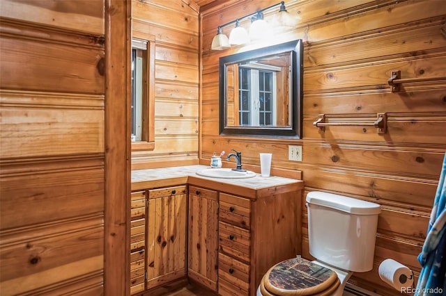 bathroom featuring vanity, toilet, and wooden walls