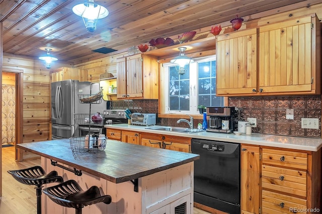 kitchen featuring sink, wooden walls, light hardwood / wood-style flooring, appliances with stainless steel finishes, and a breakfast bar area