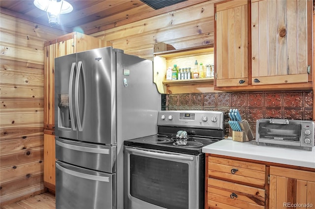 kitchen featuring wooden walls, wood-type flooring, and appliances with stainless steel finishes