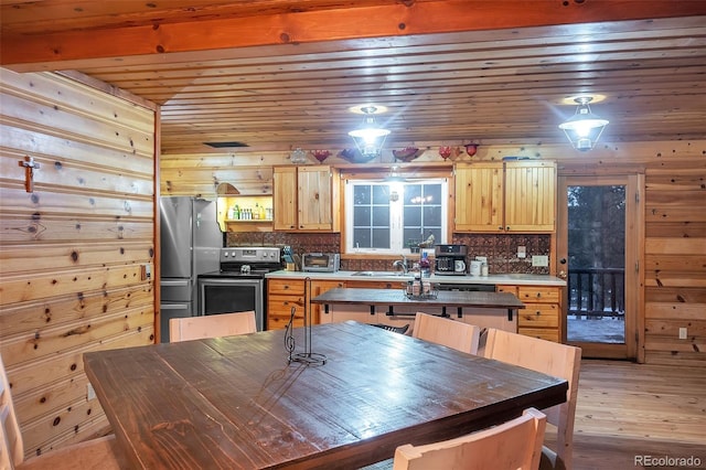 kitchen with light hardwood / wood-style floors, stainless steel appliances, wooden walls, and tasteful backsplash