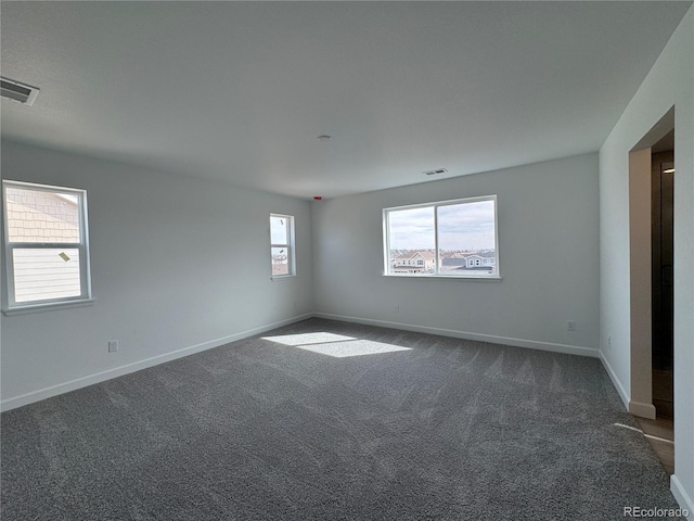 empty room featuring visible vents, baseboards, and dark colored carpet