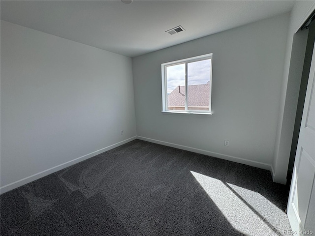 unfurnished bedroom with baseboards, visible vents, and dark carpet