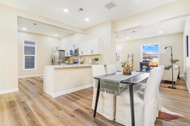 dining space featuring beam ceiling and light hardwood / wood-style flooring