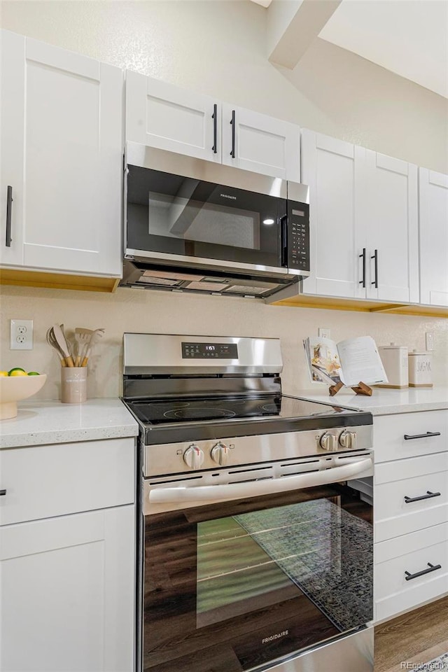 kitchen featuring white cabinets, appliances with stainless steel finishes, and wood-type flooring