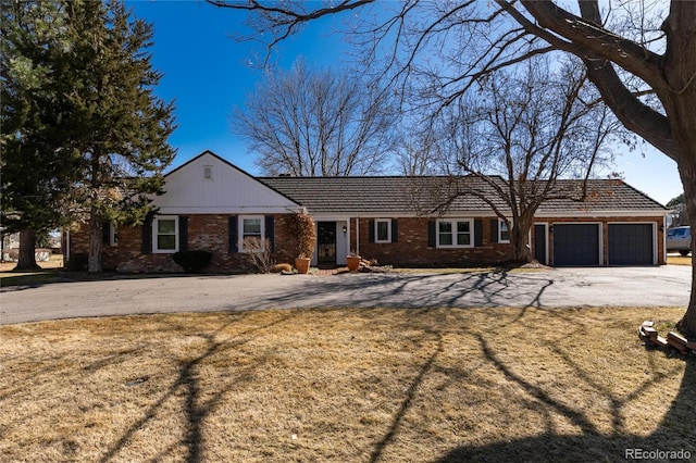 ranch-style home with aphalt driveway, brick siding, and an attached garage