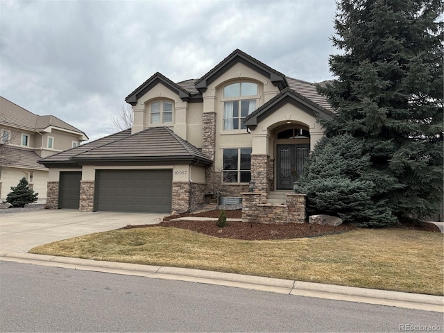 view of front of home with a garage, concrete driveway, stone siding, a front lawn, and stucco siding