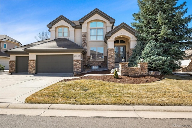 view of front of house featuring a front lawn, stucco siding, french doors, driveway, and an attached garage