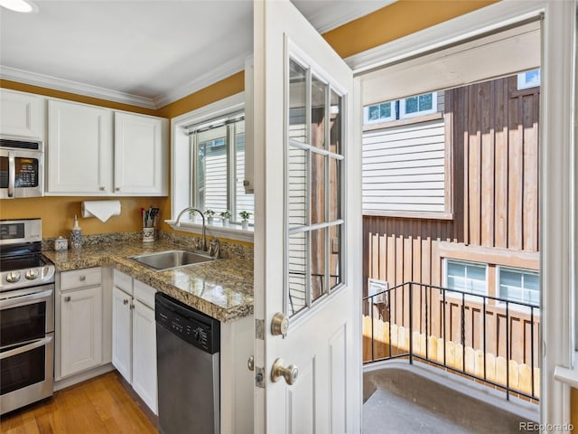 746 Birch St, Denver, CO 80220 - kitchen featuring ornamental molding, white cabinetry, a sink, light wood-style flooring, and appliances with stainless steel finishes