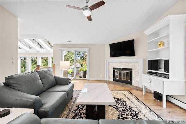 living room featuring ceiling fan, light wood-type flooring, beam ceiling, and a high end fireplace