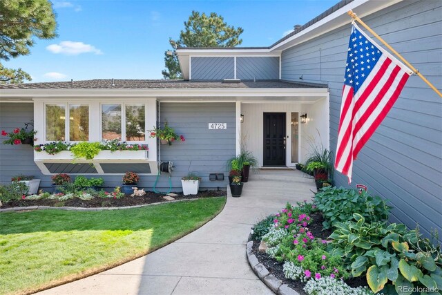 doorway to property with covered porch and a lawn