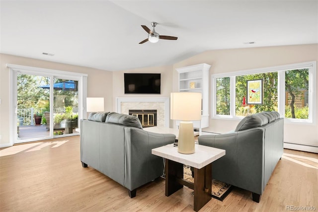 living room featuring light wood-type flooring, ceiling fan, baseboard heating, a premium fireplace, and lofted ceiling