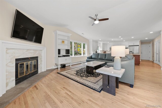 living room with a fireplace, ceiling fan, vaulted ceiling, and light hardwood / wood-style floors