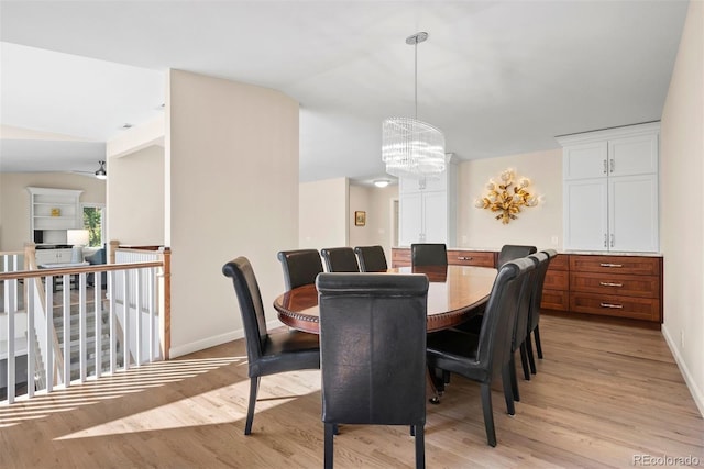 dining room with ceiling fan with notable chandelier, vaulted ceiling, and light wood-type flooring