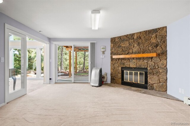 unfurnished living room with carpet floors and a stone fireplace