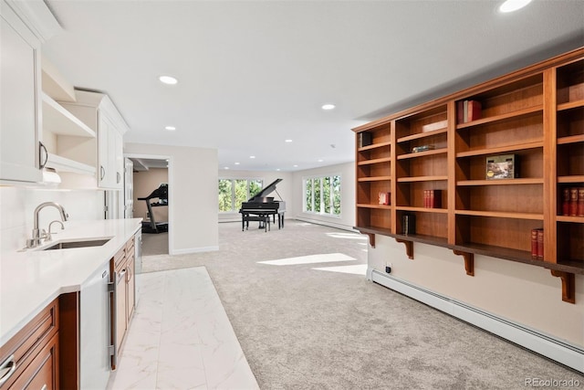 interior space featuring light colored carpet, baseboard heating, and sink