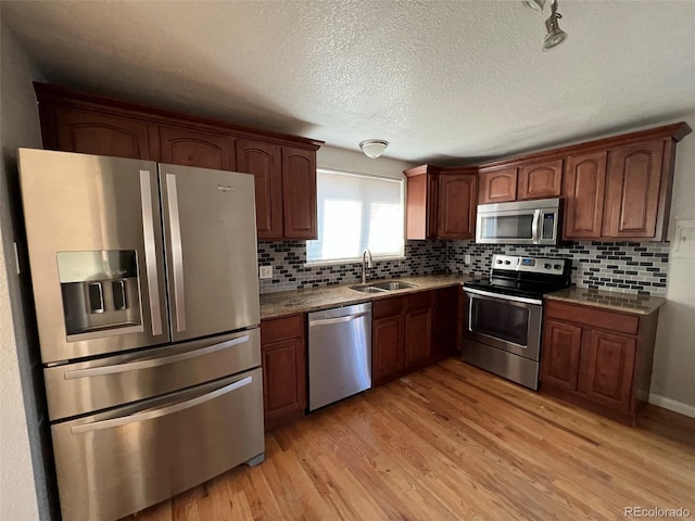 1245 Yates St, Denver, CO 80204 - kitchen featuring stainless steel appliances, light wood-style flooring, backsplash, light stone countertops, and a textured ceiling