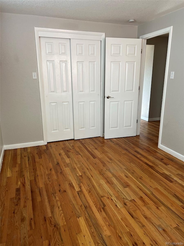 1245 Yates St, Denver, CO 80204 - unfurnished bedroom with wood finished floors, a closet, and a textured ceiling