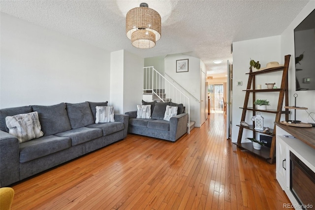 living room featuring a notable chandelier, light hardwood / wood-style flooring, and a textured ceiling